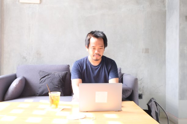 东南亚男子在咖啡馆沙发上远程工作图片下载