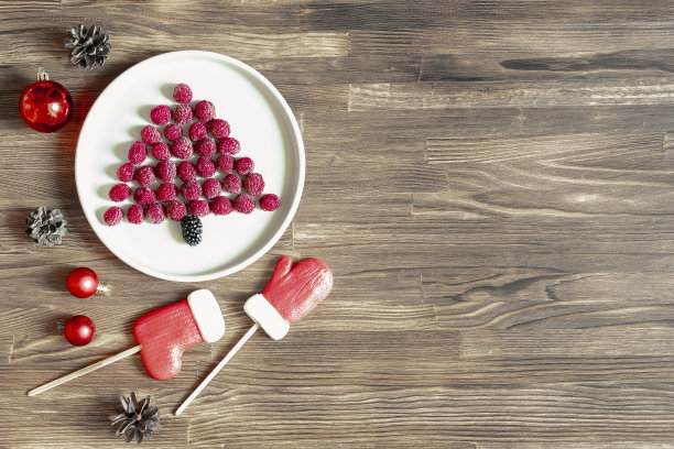 有趣的圣诞树形状的甜的新鲜覆盆子浆果在盘子上的木制背景为孩子们的早餐。圣诞食物，新年装饰，复制空间图片下载