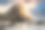 海滩上的日落，有一块大石头和海浪。图片下载