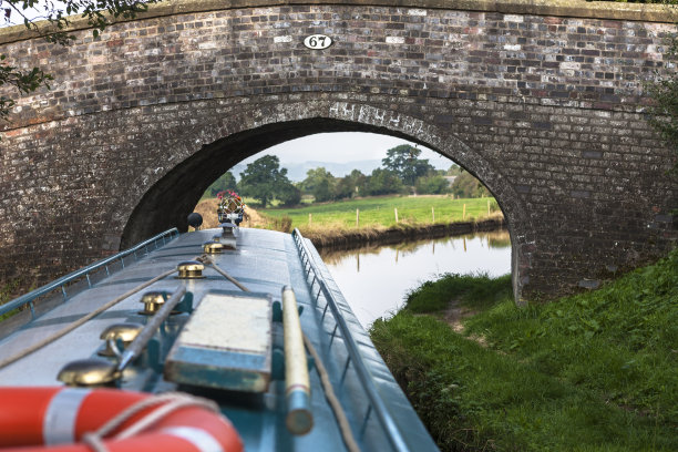 穿过针:一艘窄船通过英国什罗普郡兰格伦运河上的扫帚桥67号图片下载
