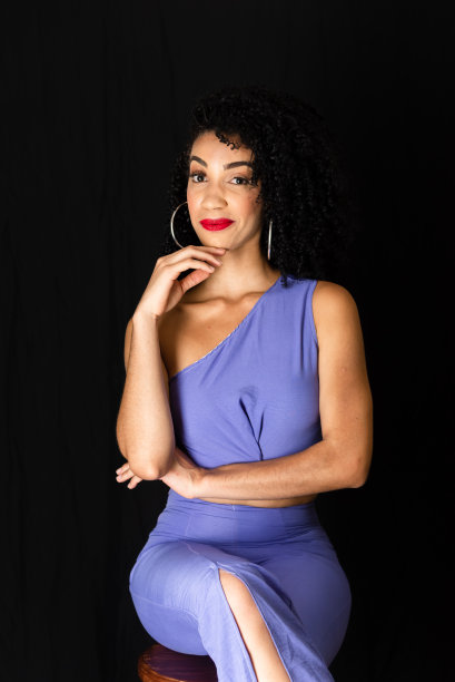 年轻漂亮的女人坐在凳子上的画像。手放在下巴上。图片下载