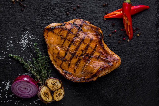 烤火鸡，红辣椒，百里香，半个红洋葱，烤大蒜，粗盐，胡椒子放在旁边。食物放在一个黑色的石板盘子里。图片下载