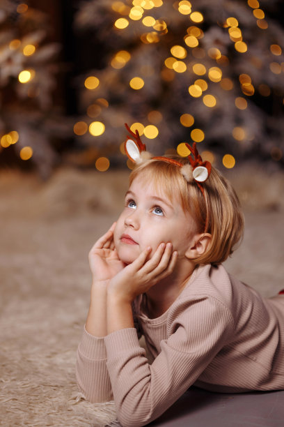 孩子躺在地板上，背景是圣诞花环图片下载