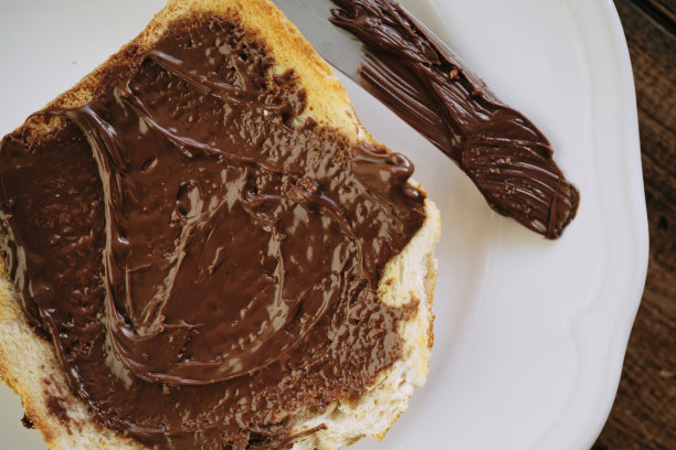 巧克力涂在白吐司上。图片下载