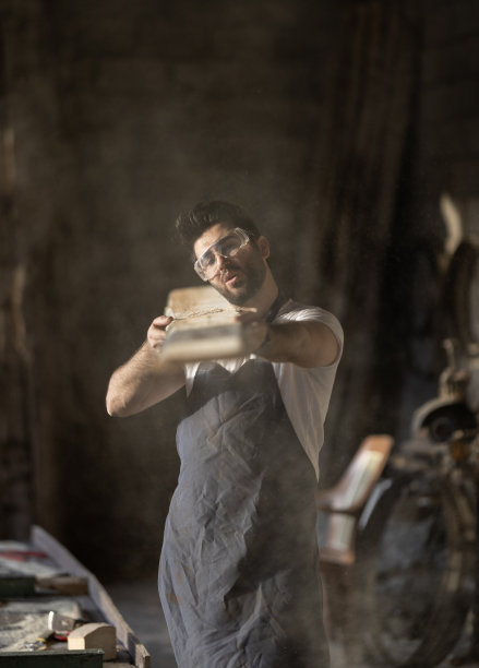 木工车间的手工工人正在吹木屑。图片下载