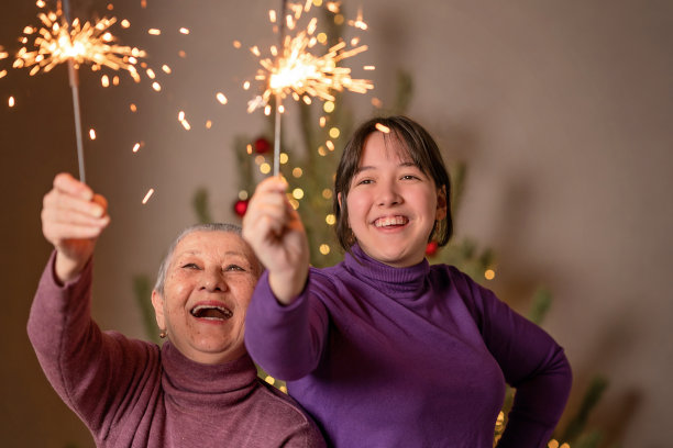 在圣诞树的背景下，人们手中燃烧的孟加拉灯。祝你圣诞快乐，新年快乐。图片下载