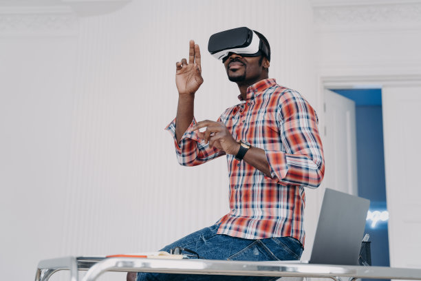戴着虚拟现实眼镜的非裔美国人软件开发人员创建了应用程序，坐在办公桌前图片下载