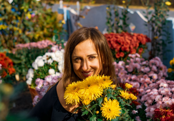 一个女人蹲在长满菊花的花坛里。图片下载