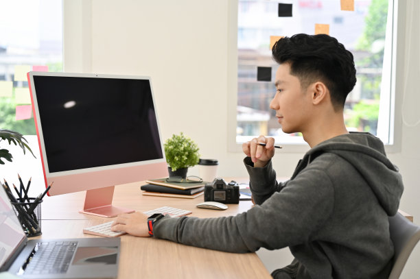 聪明的亚裔男大学生或在办公桌前工作的上班族。图片下载