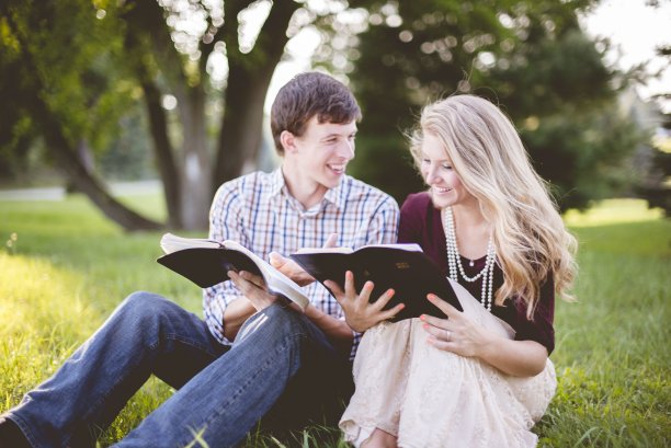 一对夫妇一起在花园里阅读圣经，阳光下，背景模糊图片下载
