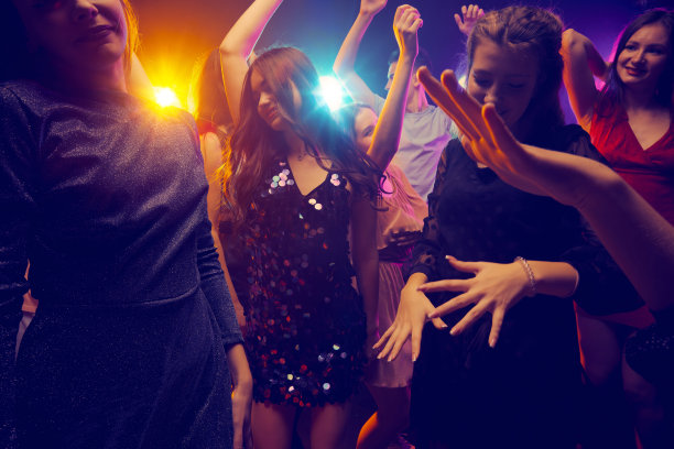 一群年轻人参加聚会，跳舞，在霓虹灯的黑暗背景下玩得很开心。周末在夜店度过图片下载