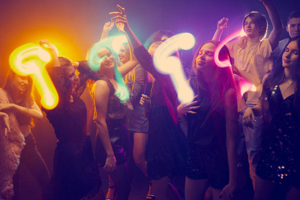 一群年轻人，女孩和男孩，参加派对，跳舞，在霓虹灯和混合光的黑暗背景上玩得很开心。学院会议图片下载