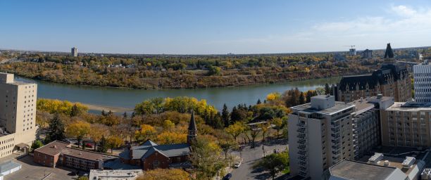 秋天，加拿大萨斯卡通的河流、密集的建筑和树木的全景照片图片下载