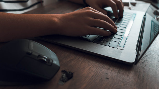 一个人在灰色笔记本电脑键盘上打字的选择性特写镜头图片下载