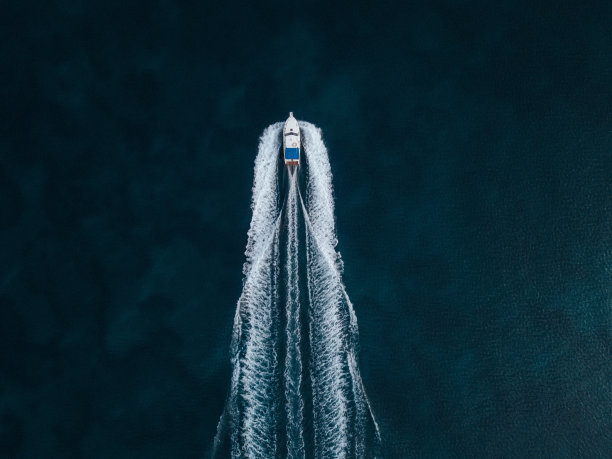 一艘摩托艇在海洋中央向前航行的空中俯瞰照片图片下载