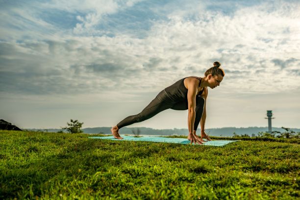 女人在草地上的瑜伽垫上伸展。健康生活方式的概念，瑜伽图片下载