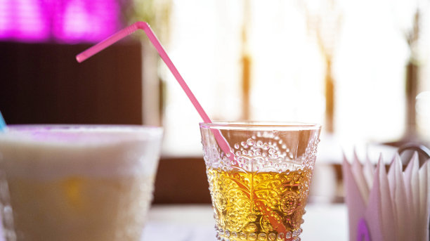 苹果汁装在杯子里，放在桌子上，有一根吸管，背景是窗户和阳光。夏天喝。文本的复制空间图片下载