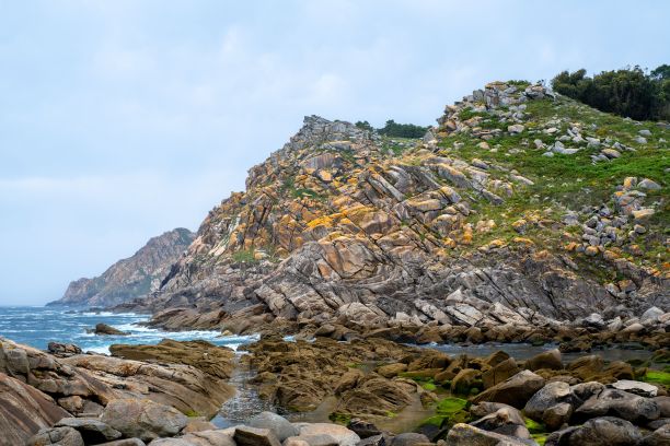 海边一座小山的美丽照片，黄色的岩石和绿色的草图片下载