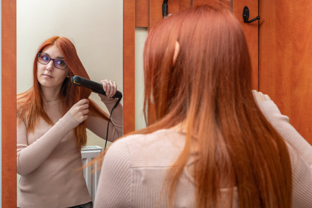 一位年轻女子正对着镜子烫头发图片下载