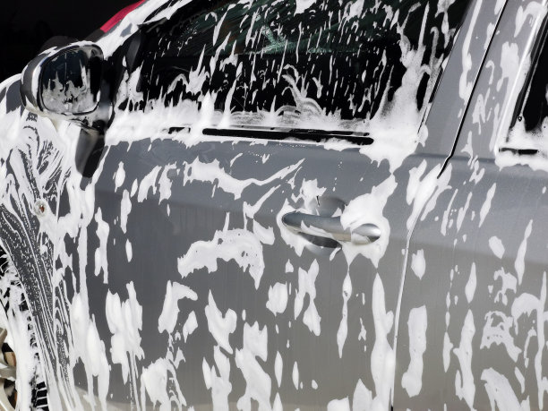 用白色肥皂和泡沫涂在车身上洗车的画面。图片下载