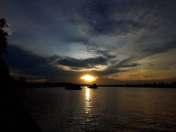 河面上美丽的夕阳和一些船只的剪影。图片下载