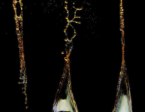 橙汁、柠檬汁或油润滑剂飞溅，液体金黄色饮料滴。水果饮料水元素呈直线形式。新鲜的飞溅和流动的射流，黑色背景孤立的冻结运动图片下载