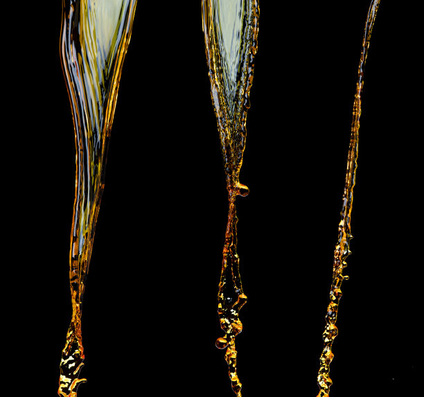 橙汁、柠檬汁或油润滑剂飞溅，液体金黄色饮料滴。水果饮料水元素呈直线形式。新鲜的飞溅和流动的射流，黑色背景孤立的冻结运动图片下载