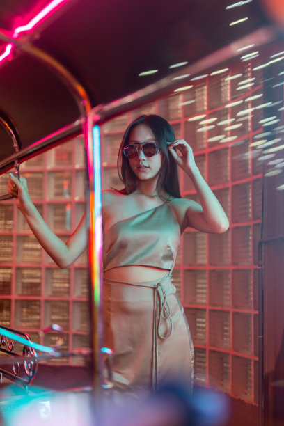 工作室肖像照片的美丽年轻的亚洲女性模特穿着优雅的衣服和太阳镜与冷静的情绪看站在一辆嘟嘟出租车车辆旁边图片下载