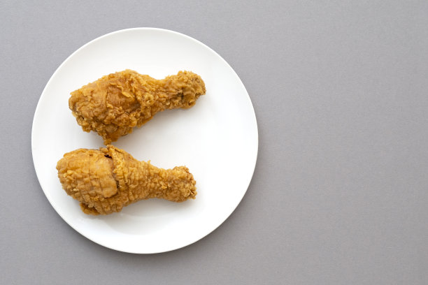 两个烤鸡腿或鸡腿放在白色陶瓷盘上，俯视图图片下载