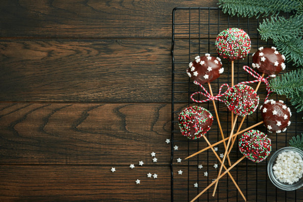 嫁给圣诞甜棒棒糖蛋糕。圣诞甜点圆形布朗尼棒棒糖蛋糕，深绿色背景上点缀着星星。圣诞美食甜品概念与场景宽屏假日边界。俯视图图片下载