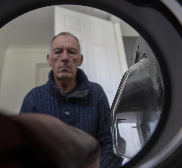 老人正在把衣物放进洗衣机图片下载