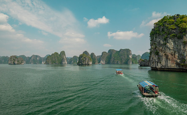 在越南，有屋顶的木船在海上被岩石包围的美丽照片图片下载