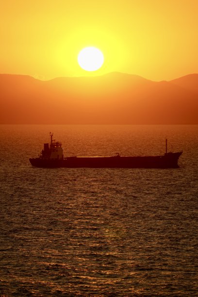 海上夕阳西下，工业船停在路边。船在日落时出海。红日照进了船停泊的山海。日本海的日落。图片下载