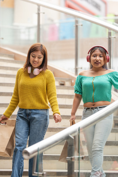 两个朋友提着购物袋走下楼梯图片下载