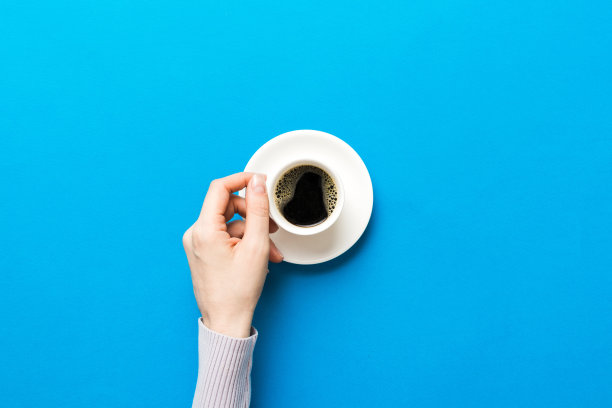 极简风格的女人手拿一杯咖啡在彩色背景。平铺，俯视浓缩咖啡杯。文字空白的地方，复制的空间。咖啡上瘾。俯视图，平铺图片下载