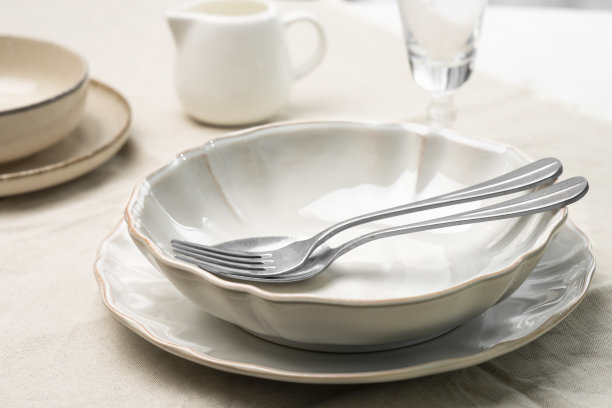 一张铺着桌布的桌子上有一个空盘子和一个勺子和叉子。工作室从低角度拍摄。图片下载