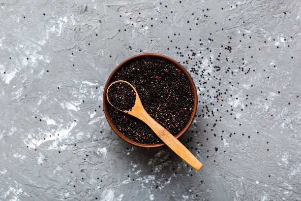 在碗和勺子里的藜麦种子在彩色背景上。健康的kinwa在小碗里。健康的超级食物图片下载