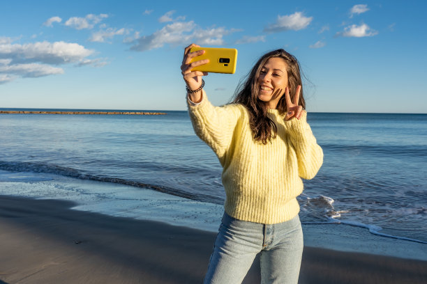 一个有吸引力的快乐的女性在海滩上拍照的选择性聚焦镜头图片下载