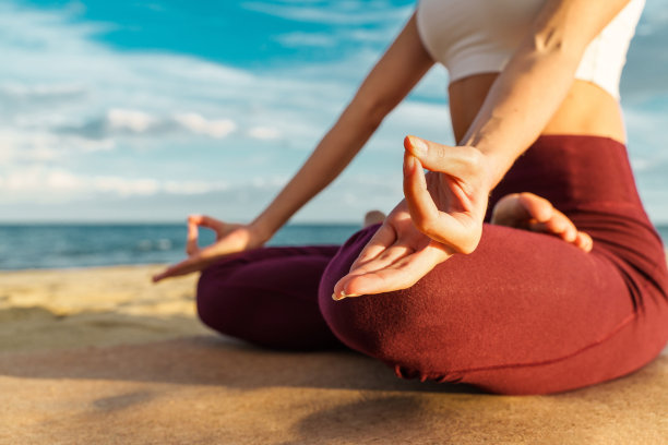 日落时分在海滩上冥想的女人-手的特写-剪影-无法辨认的人图片下载