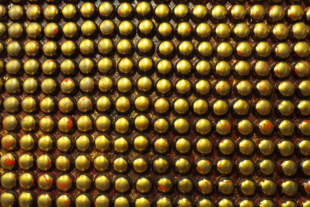 由黑色和金色金属制成的青春痘或青春痘。金属大圆型凸起的几何位置。不寻常的工业抽象链甲背景。图片下载