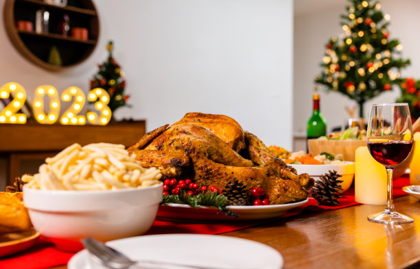 家人在圣诞晚会上用葡萄酒、香槟庆祝圣诞夜快乐。烤感恩节火鸡配菜。感恩节庆祝活动。图片下载