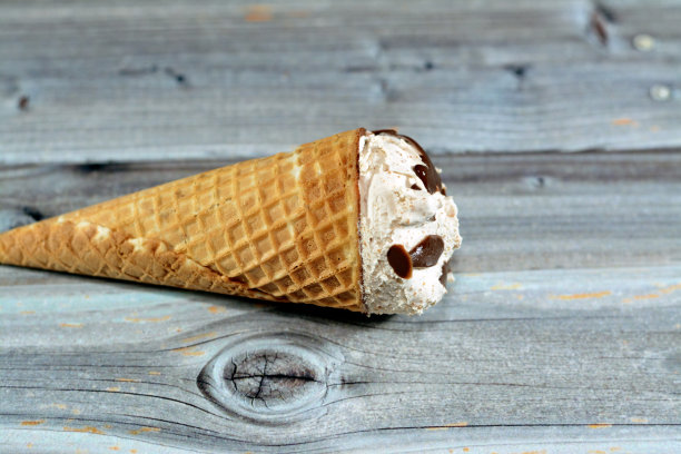 香草冰淇淋蛋卷，带有巧克力碎片，威化饼干锥中融化的冰淇淋特写图片下载