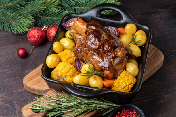 节日晚餐:烤土豆和玉米配猪小腿肉，圣诞新年装饰的节日食物图片下载