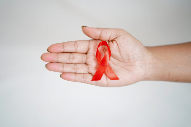 一名妇女一手拿着红丝带，代表世界艾滋病毒/艾滋病日、健康概念、艾滋病毒/艾滋病意识图片下载