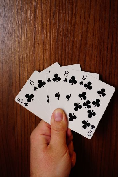 垂直的一个人持有俱乐部扑克卡片与各种黑色的木制背景图片下载