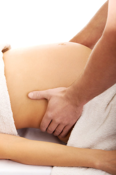 在白色背景下，一名男子给孕妇做腹部按摩图片下载