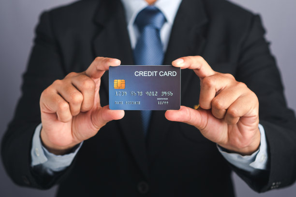 商人拿着一个蓝色的信用卡模型站在一个工作室图片下载