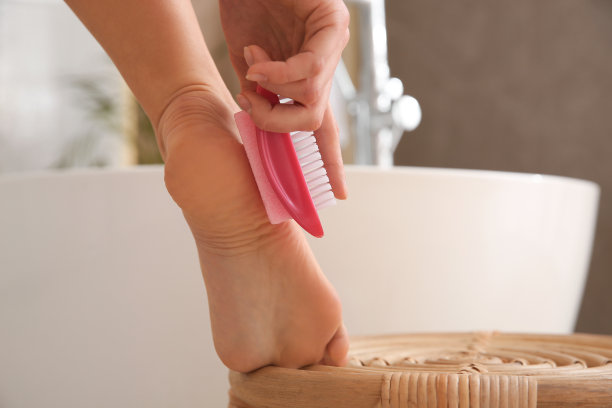 女子在浴室用浮石去除脚上的死皮，特写图片下载