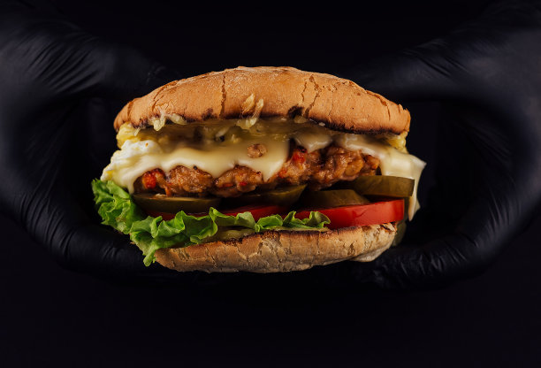 男子戴着黑色手套，手里拿着美味的汉堡图片下载