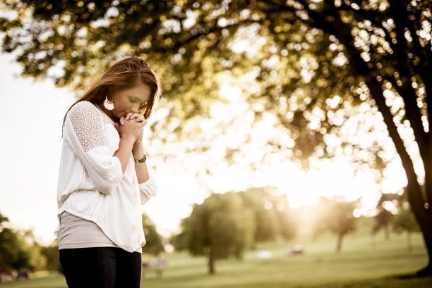 特写镜头，一个女人闭着眼睛祈祷，背景模糊图片下载